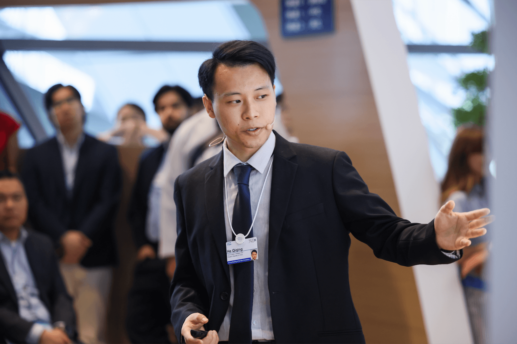 Qiqing He speaking with a headset microphone during an AMNC 2026 future-of-work session