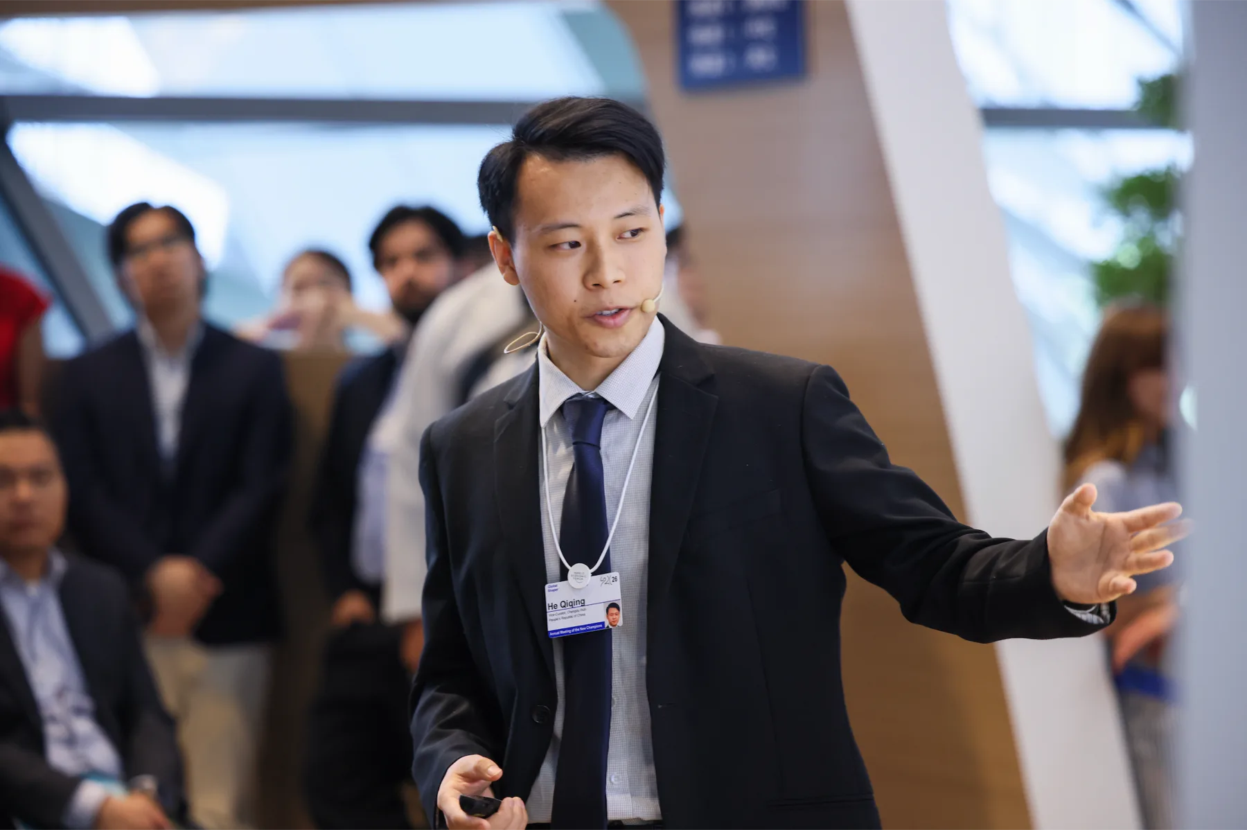 Qiqing He speaking with a headset microphone during an AMNC 2026 future-of-work session